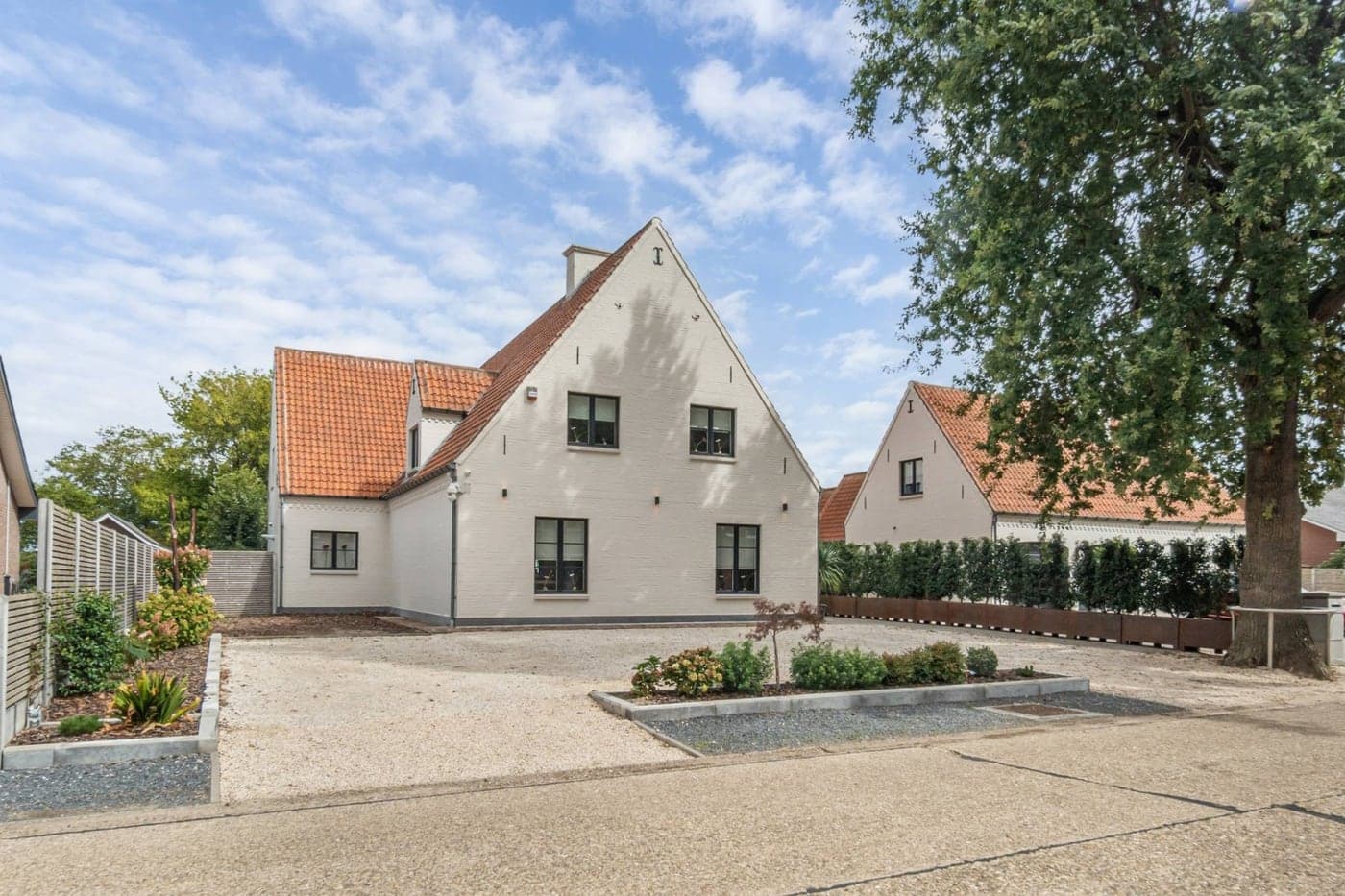 Een witte woning met een verzorgde grindoprit, mooi in beeld gebracht