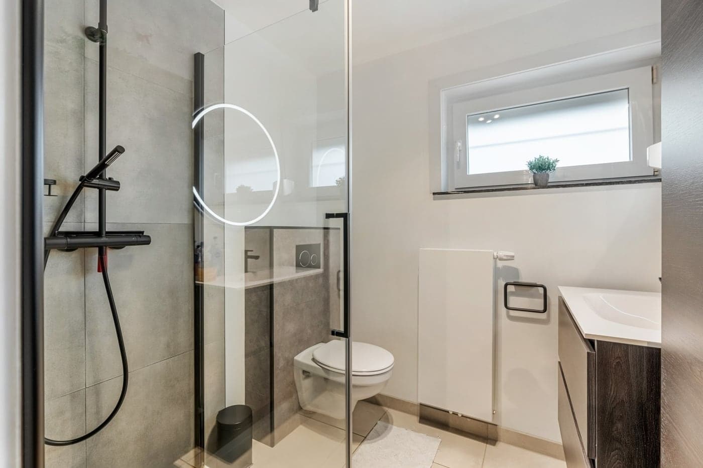 Een strakke, blinkend propere badkamer met glazen douche