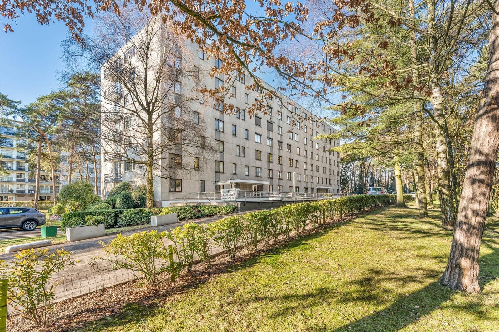 Een appartementsgebouw tussen de bomen aan de Weg naar As in Genk, verkocht door Mano Immo