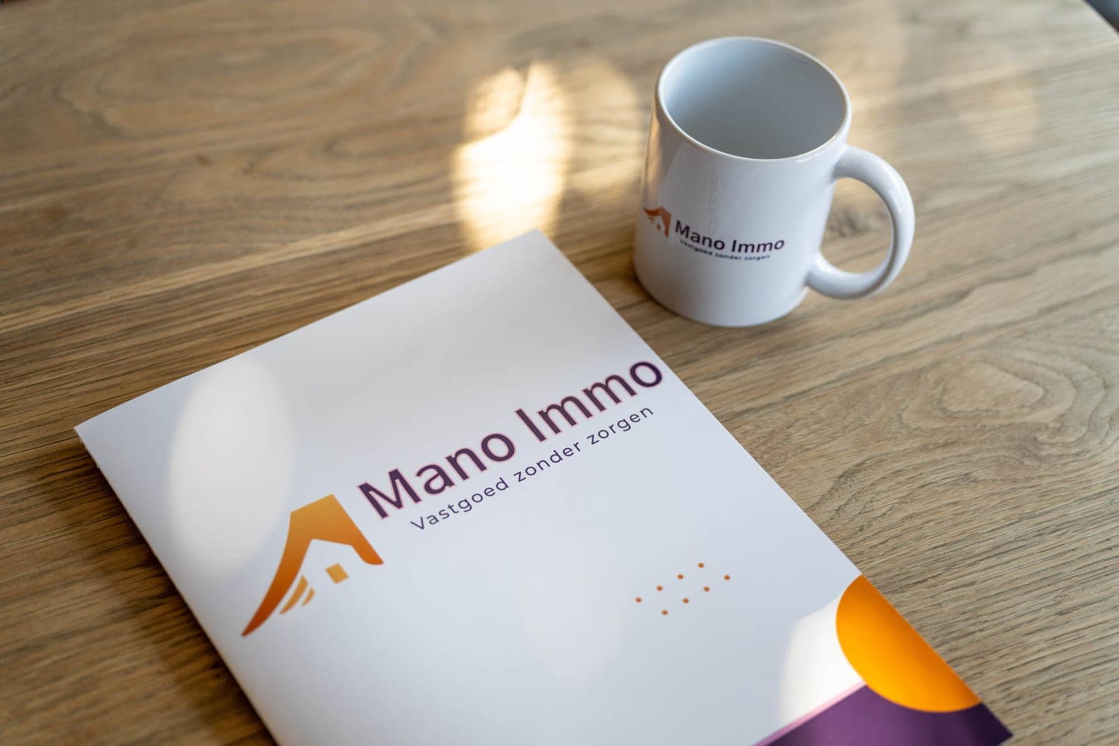 Een map van Mano Immo en een koffiekop op tafel