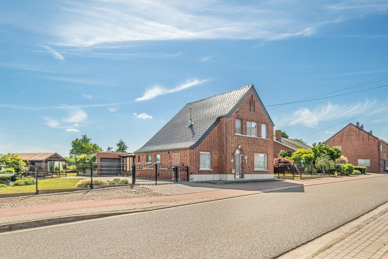 Een oudere bakstenen woning met tuin langs de straat