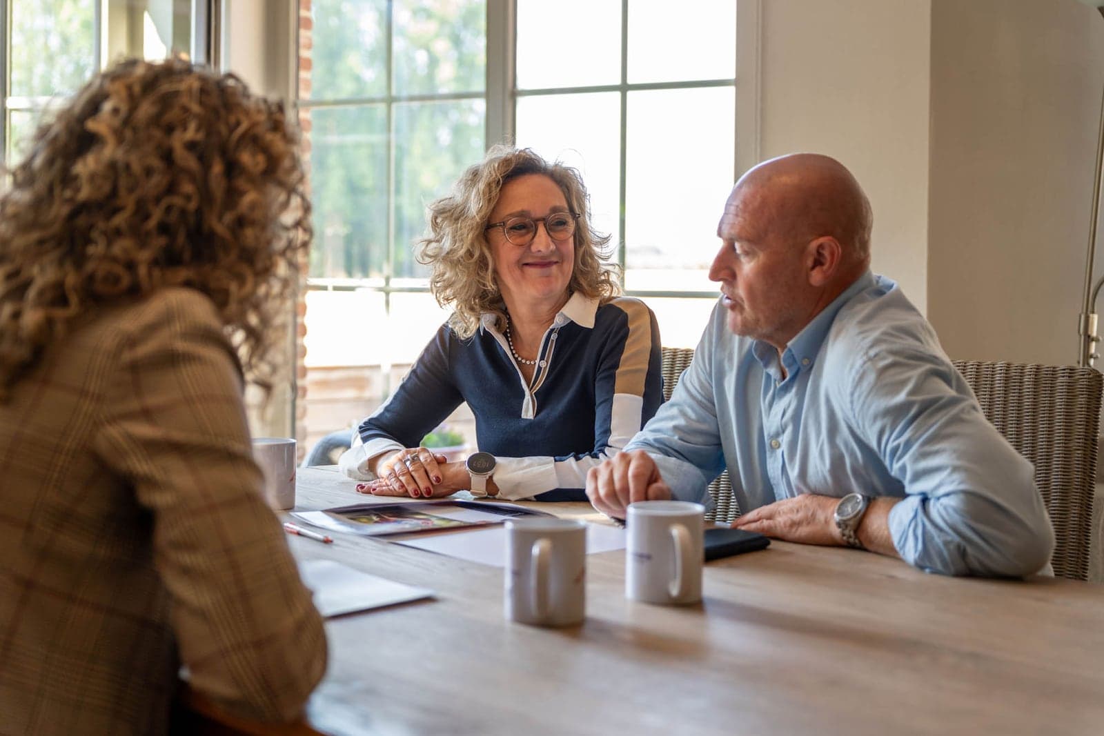 Tiziana in gesprek met een koppel aan de keukentafel