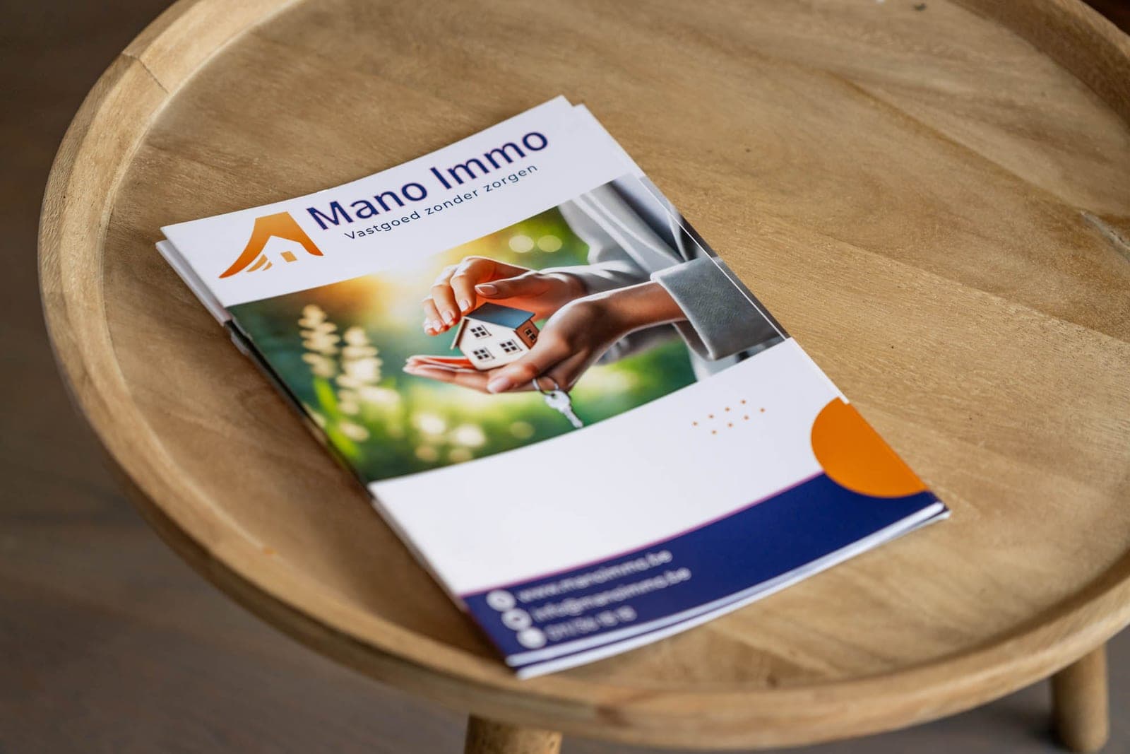 Een brochure van Mano Immo op een ronde tafel
