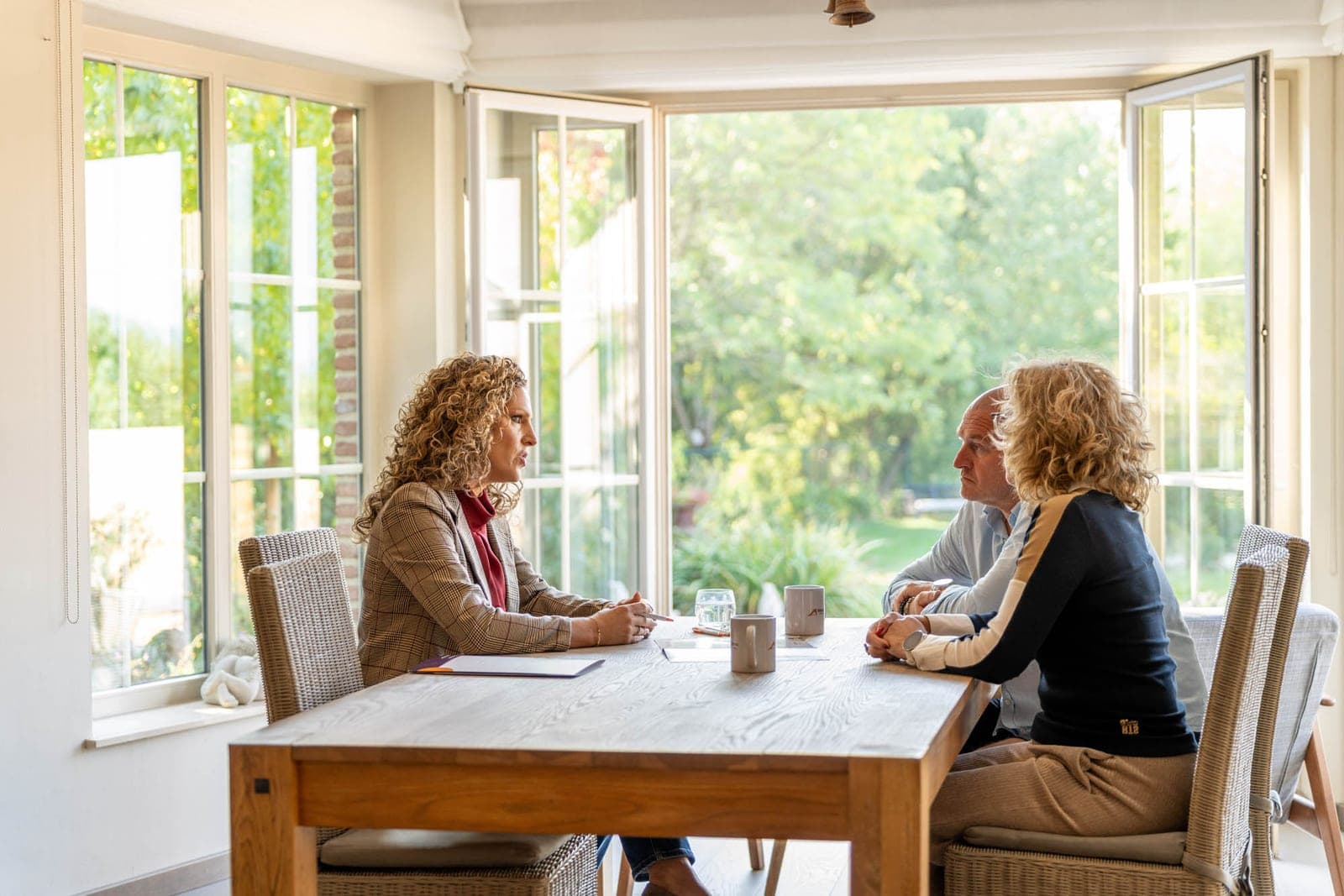 Tiziana in een rustig gesprek met familie aan tafel in een lichte serre
