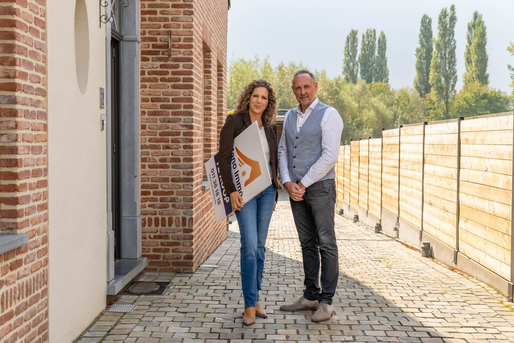 Tiziana en Hans met het Mano Immo te-koopbord voor een woning